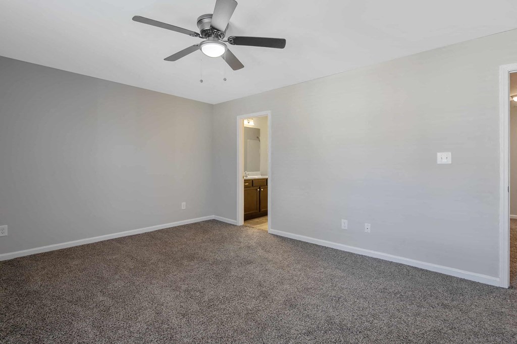 an empty living room with a ceiling fan