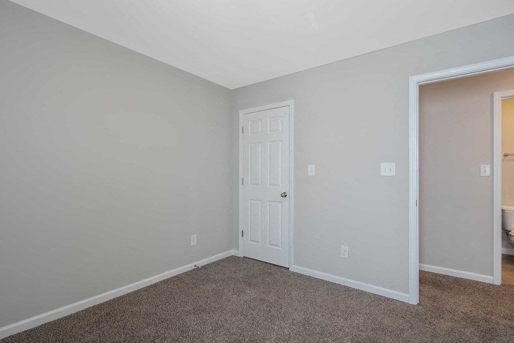 a bedroom with a white door and a door to a closet