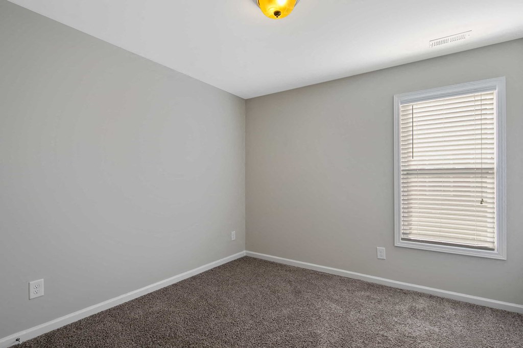 an empty room with a window and carpet