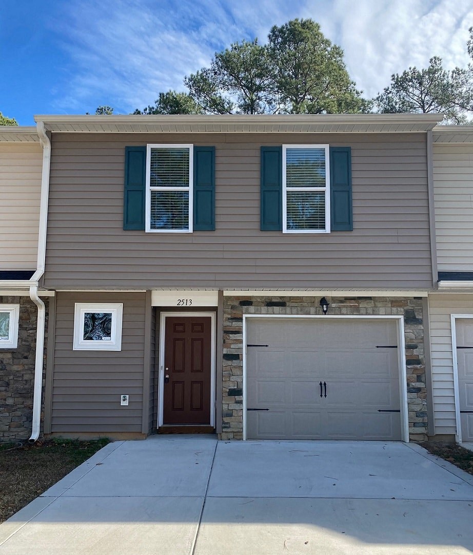 a tan house with a garage door in front of it