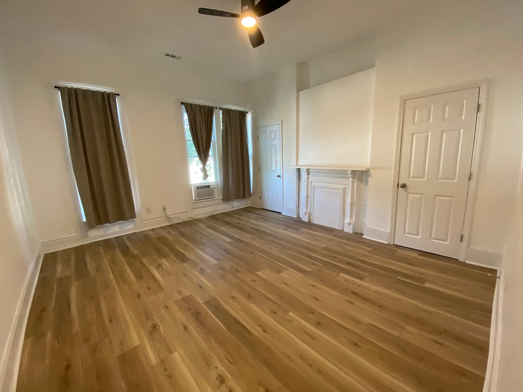 A room with wooden flooring and white walls.