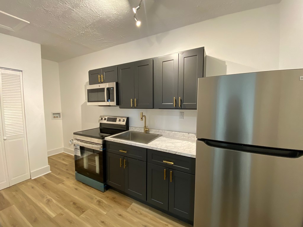 A kitchen with a stainless steel refrigerator, microwave, oven, and cabinets.