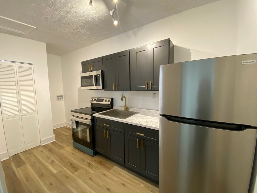 A kitchen with a stainless steel refrigerator, microwave, oven, and cabinets.