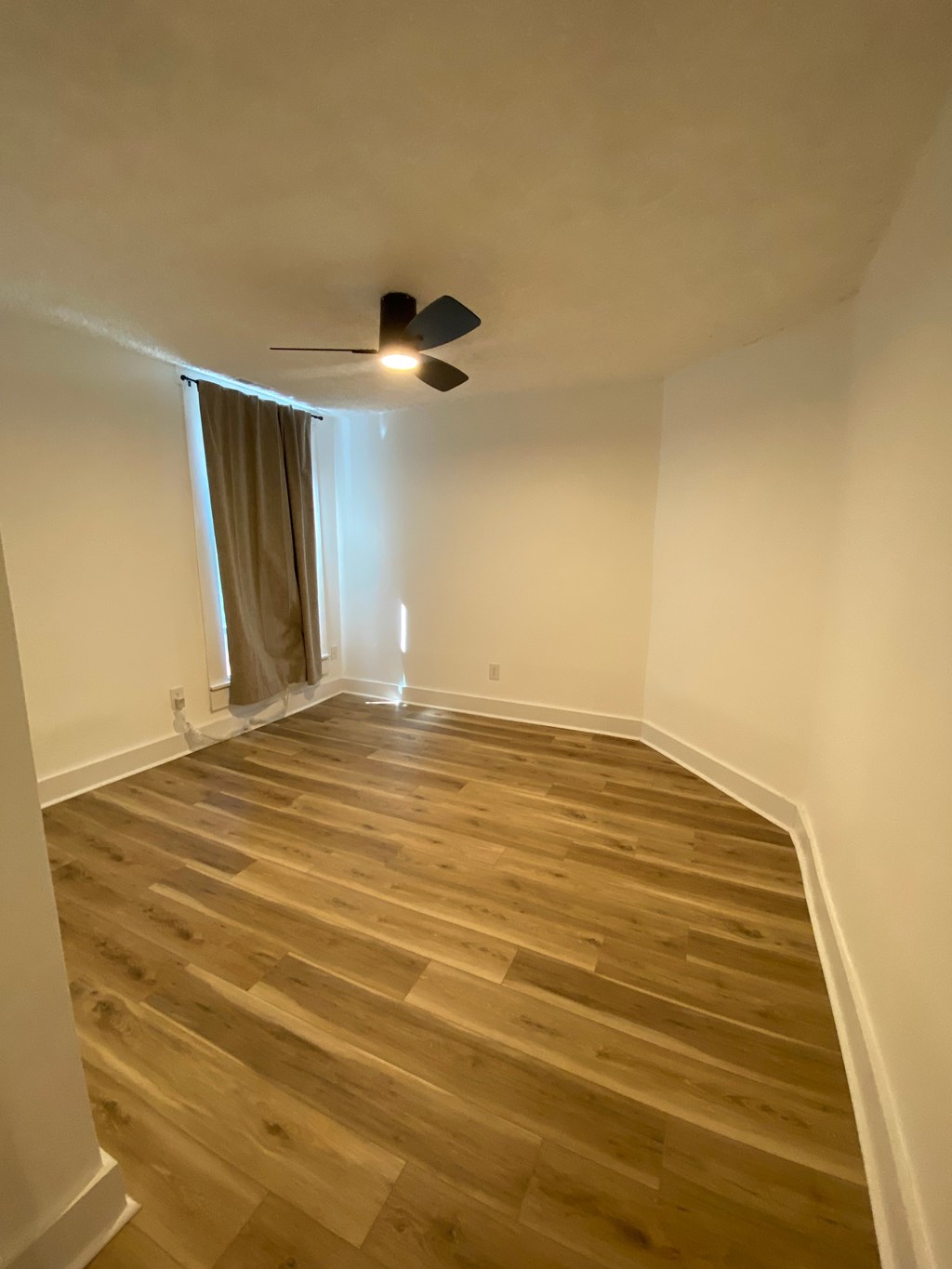 A room with a ceiling fan and wooden flooring.