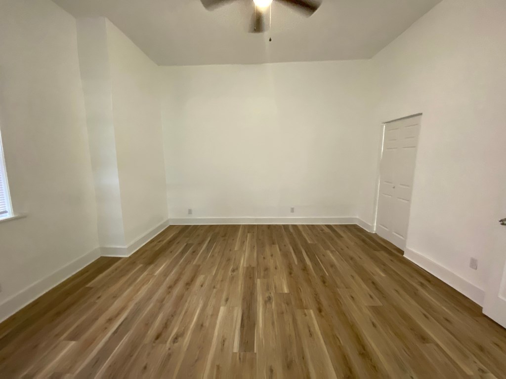 A room with wooden flooring and a ceiling fan.