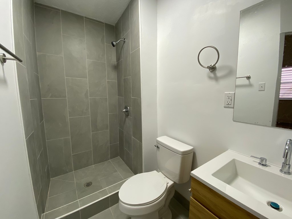 A bathroom with a toilet, sink, and shower.