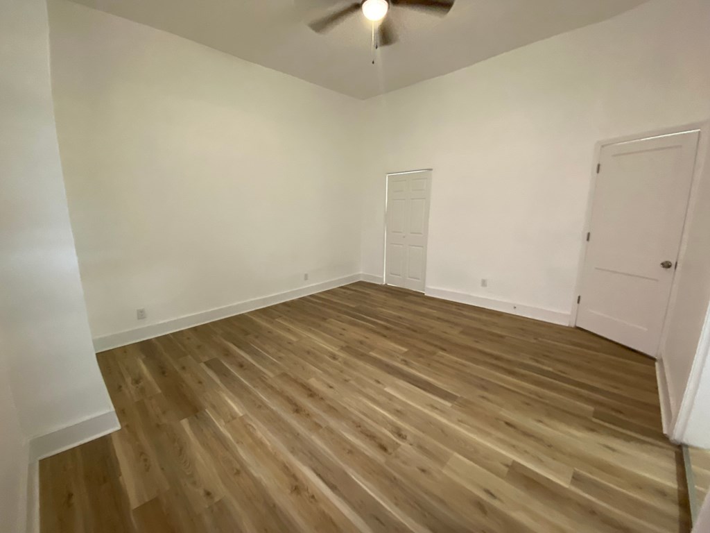 A room with wooden flooring and a ceiling fan.