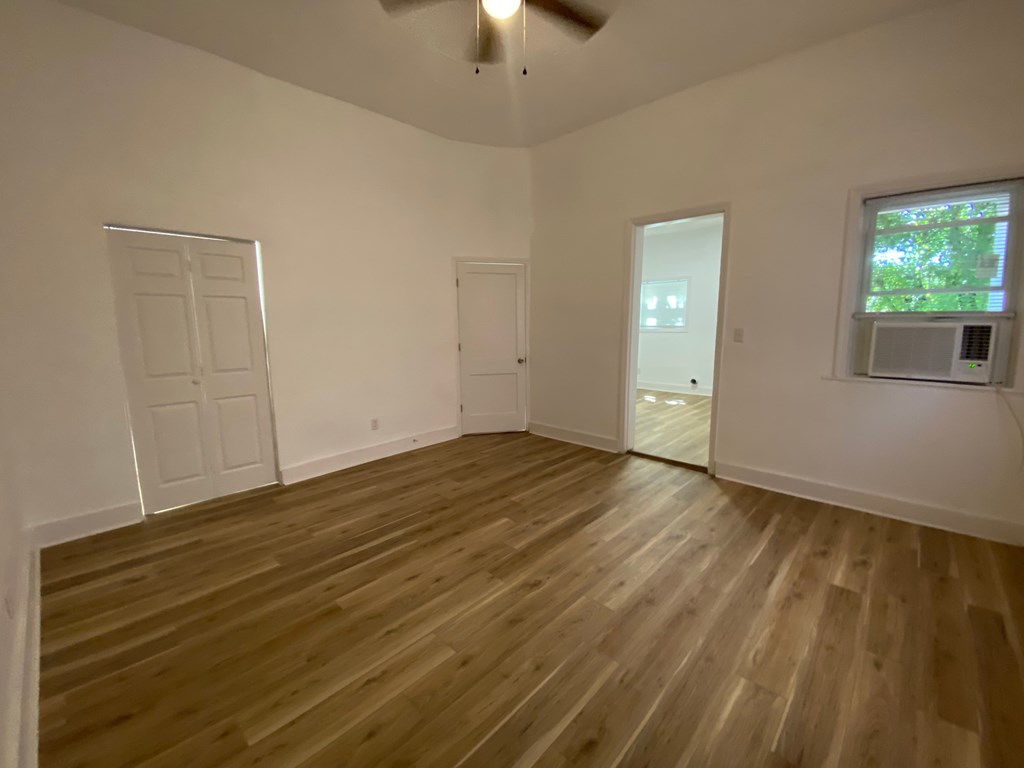 A room with wooden flooring and a ceiling fan.