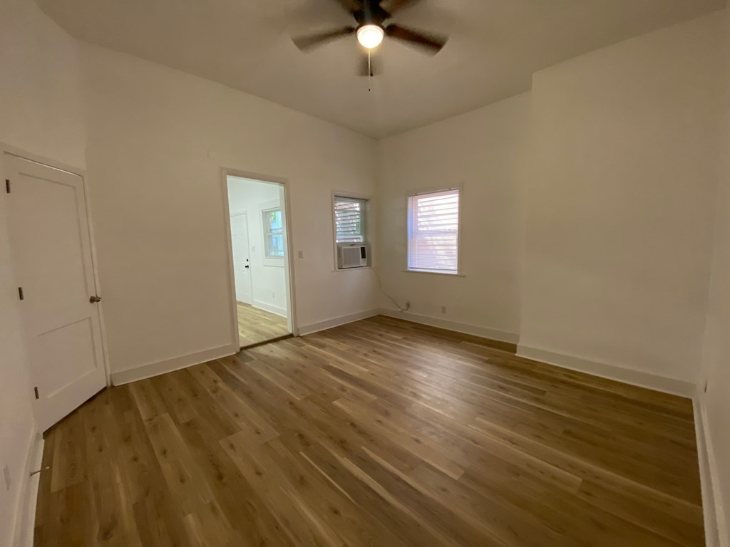A room with wooden flooring and a ceiling fan.