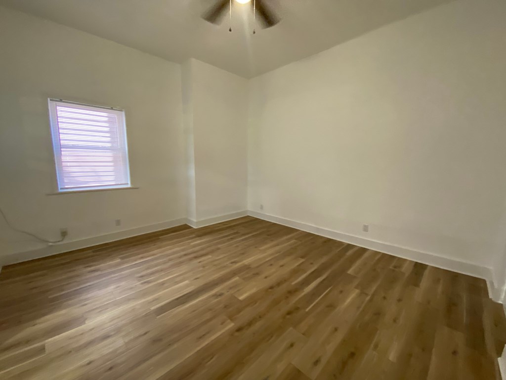 A room with wooden flooring and a window with blinds.