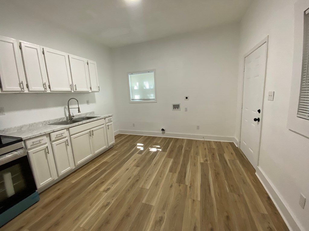 A kitchen with wooden floors and white cabinets.