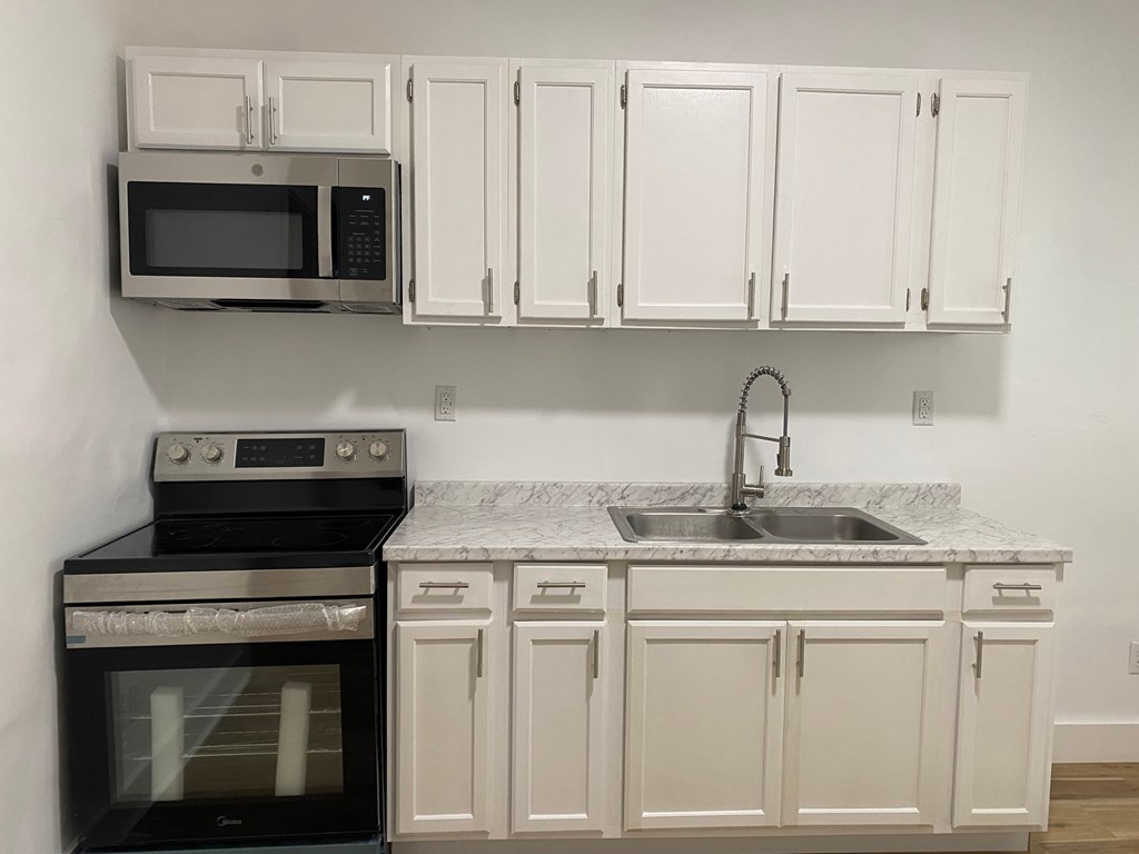 A kitchen with white cabinets and a black stove top oven.