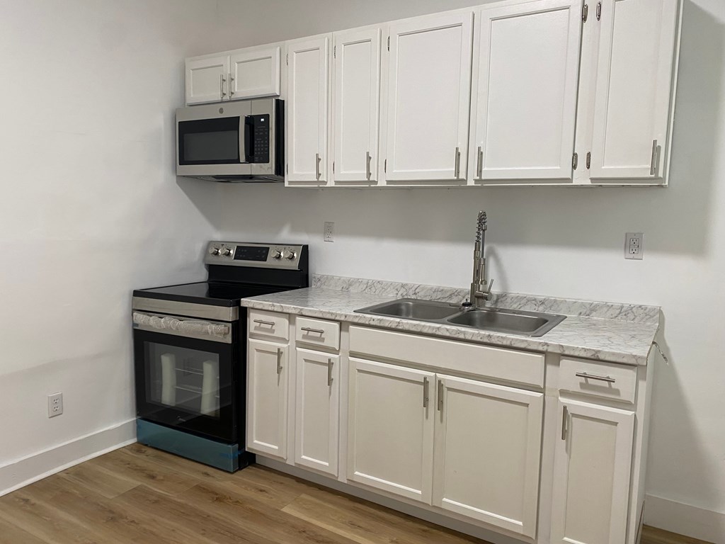 A kitchen with white cabinets and a black oven.