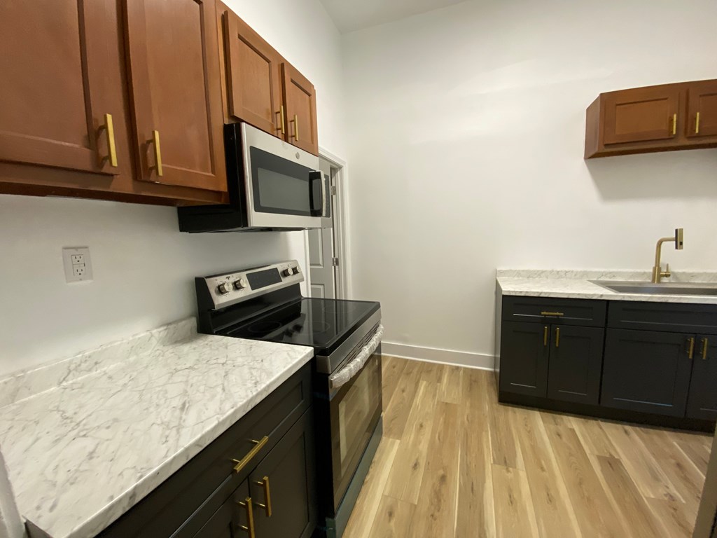 A kitchen with black cabinets and a white marble countertop.