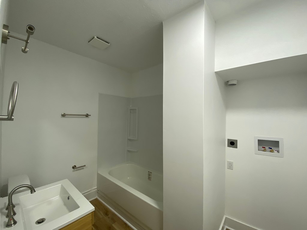 A white bathroom with a tub, sink, and towel rack.
