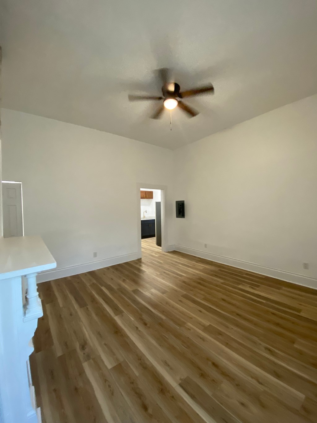 A room with a ceiling fan and wooden flooring.