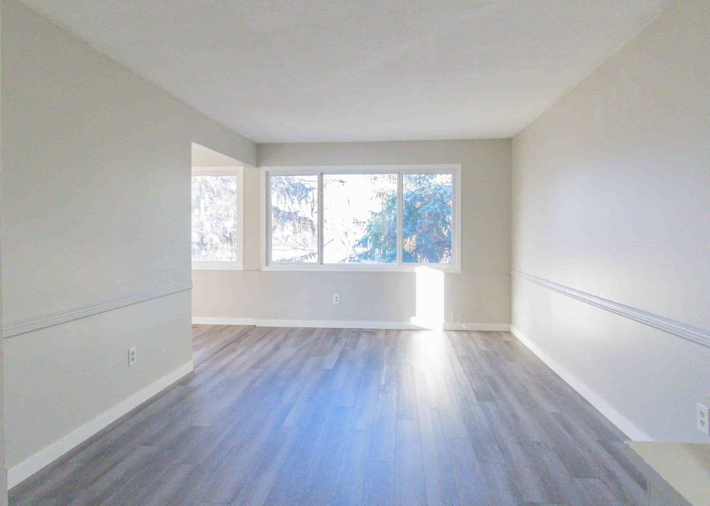 an empty living room with white walls and a window