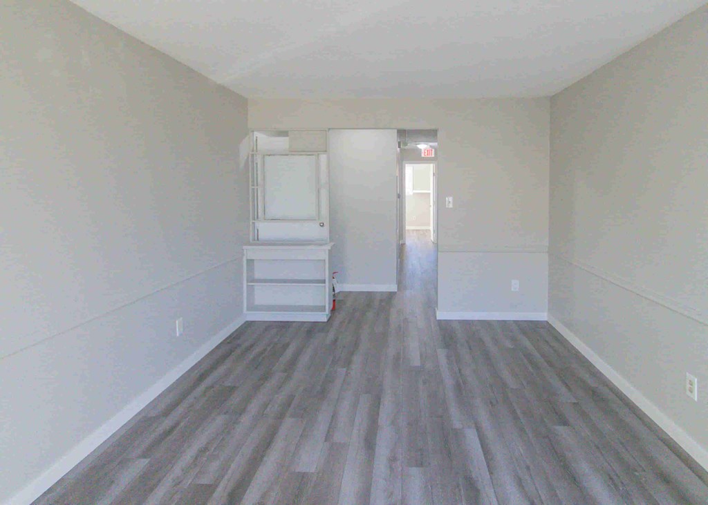 an empty room with a wooden floor and white walls