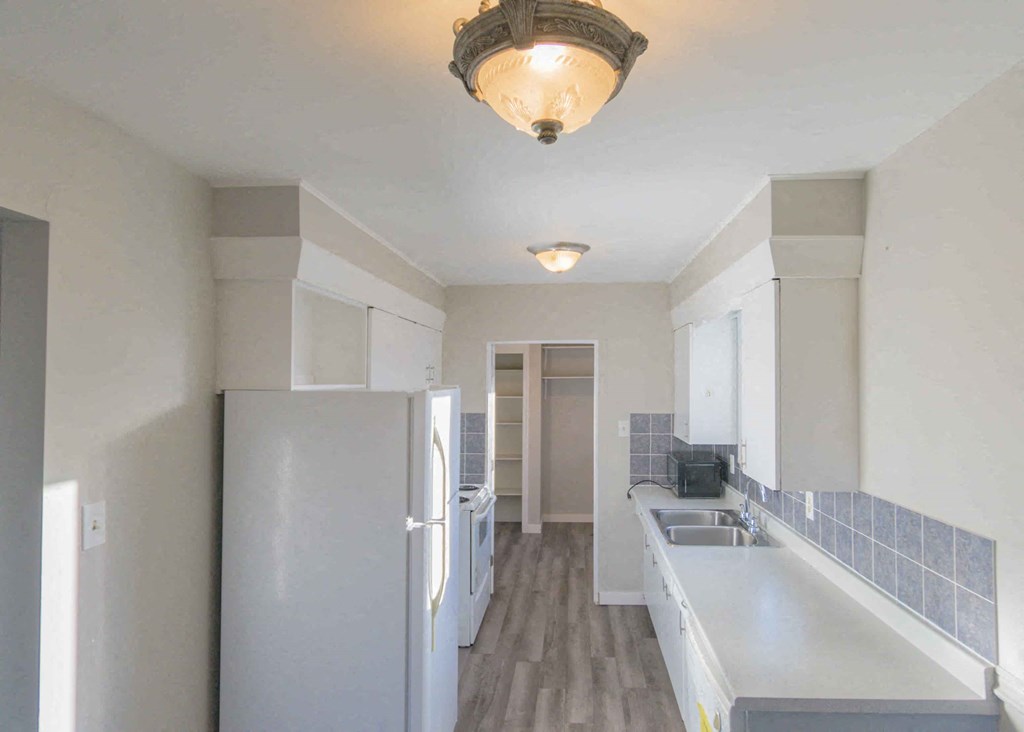 a kitchen with white cabinets and a refrigerator and a sink