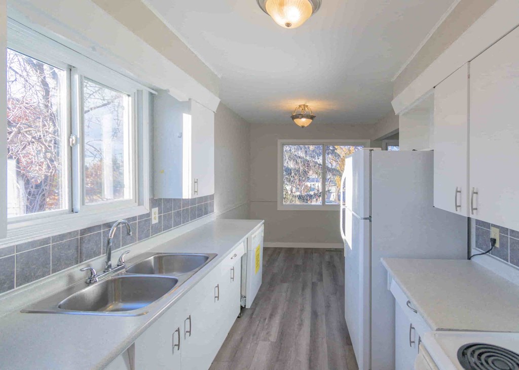 a kitchen with white cabinets and a sink and a refrigerator