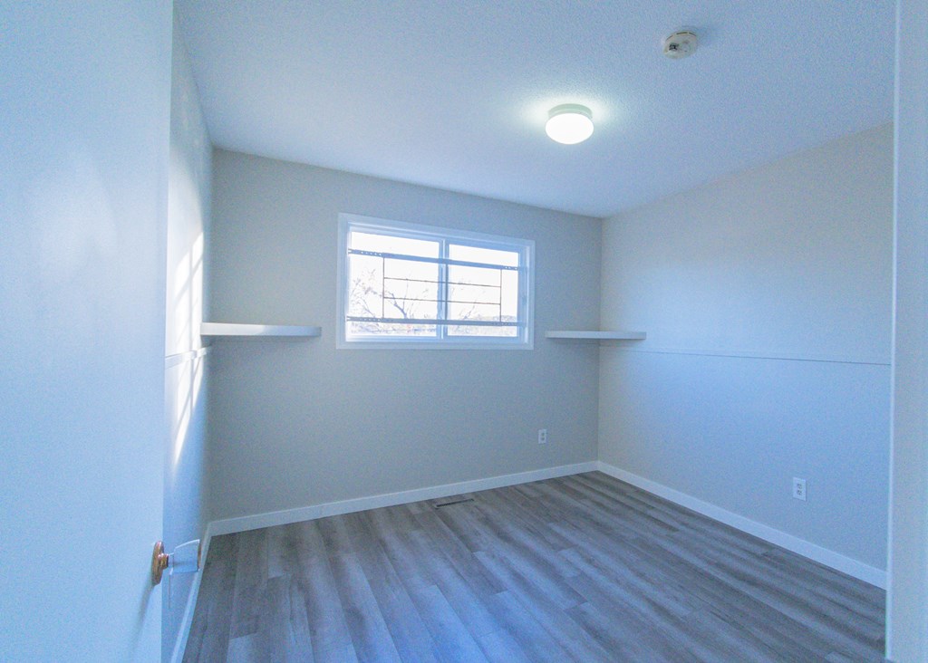 an empty room with white walls and a window