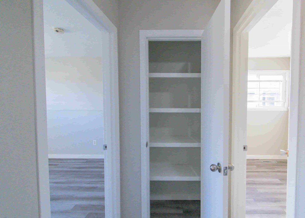 a closet with white shelves and a glass door