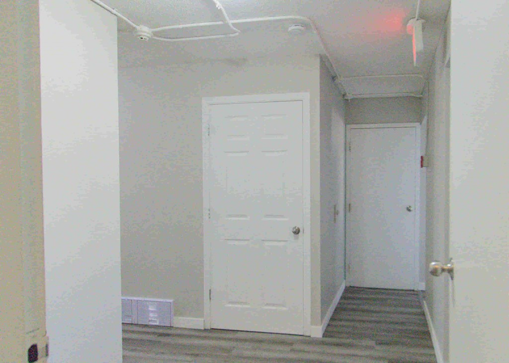 an empty hallway with a white door and stairs