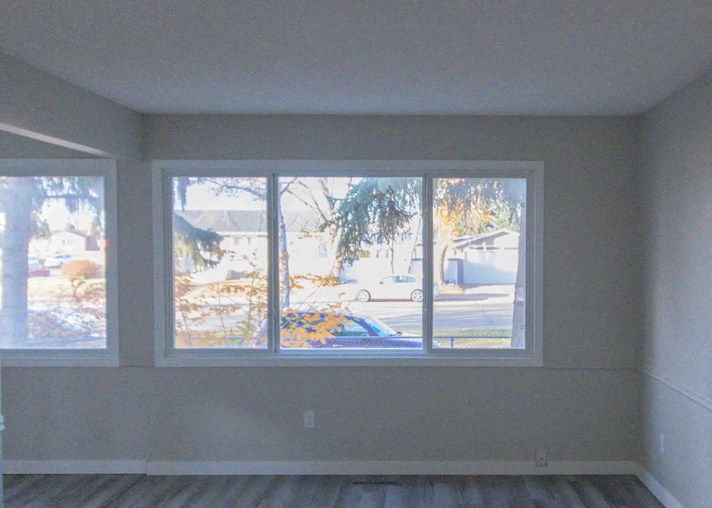 large windows in an empty living room with wood floors