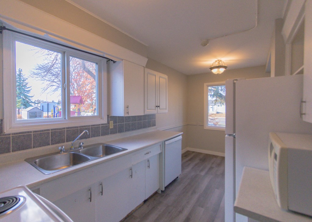 a kitchen with white cabinets and a sink and a refrigerator