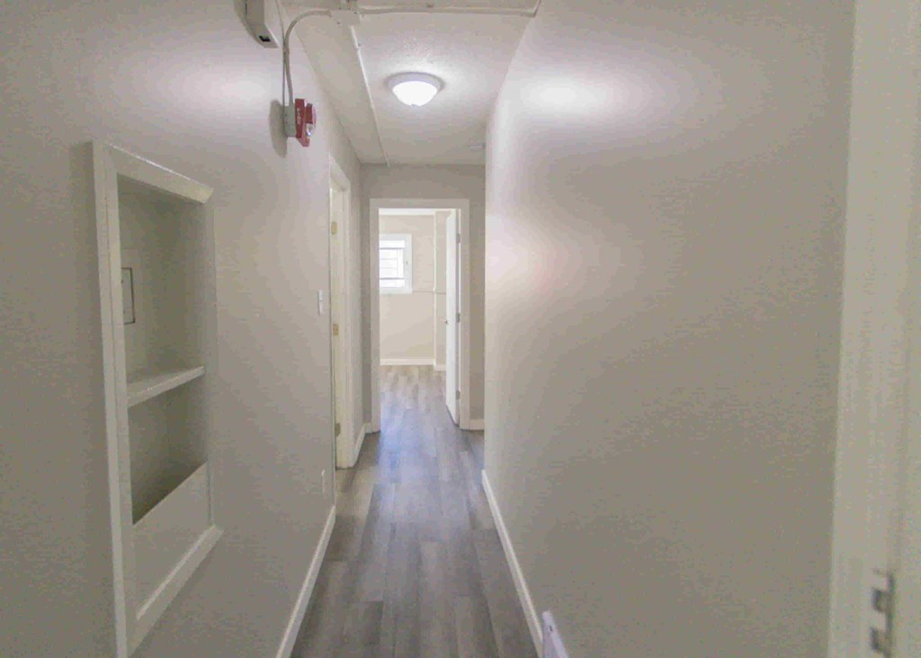 a long hallway with a wood floor and white walls and a white corridor with a