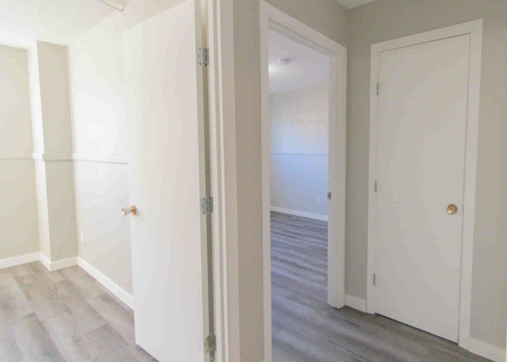 a bedroom with white closets and a wood floor