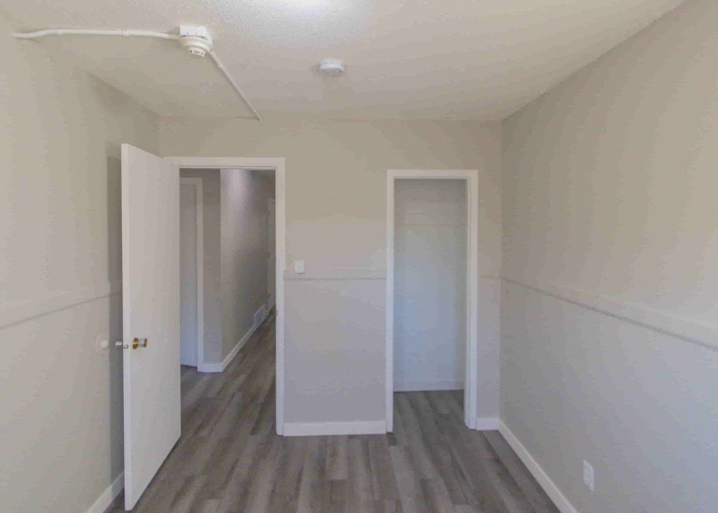 a room with white walls and wood floors and two doors