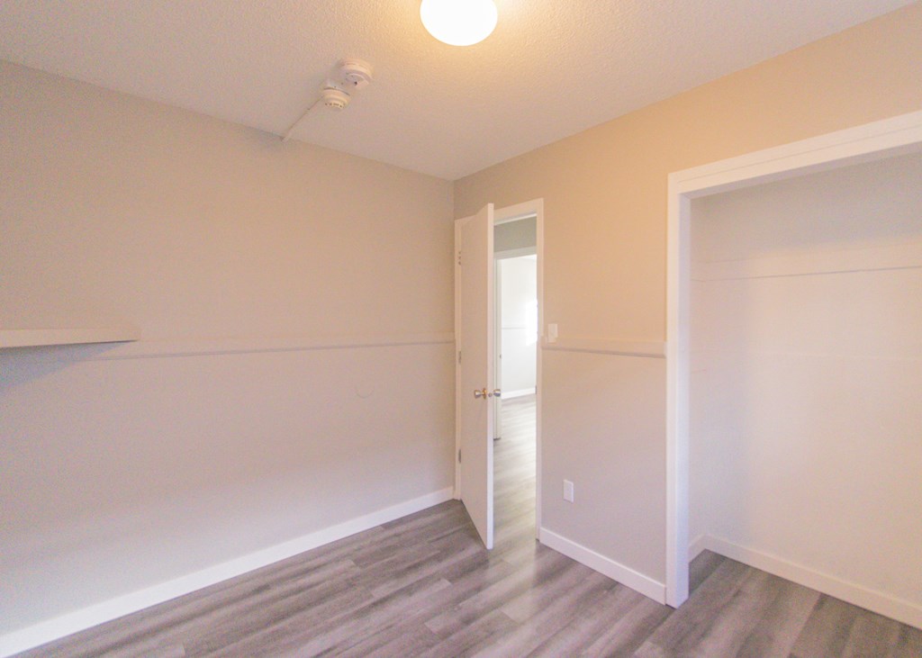 an empty room with a door open to a closet