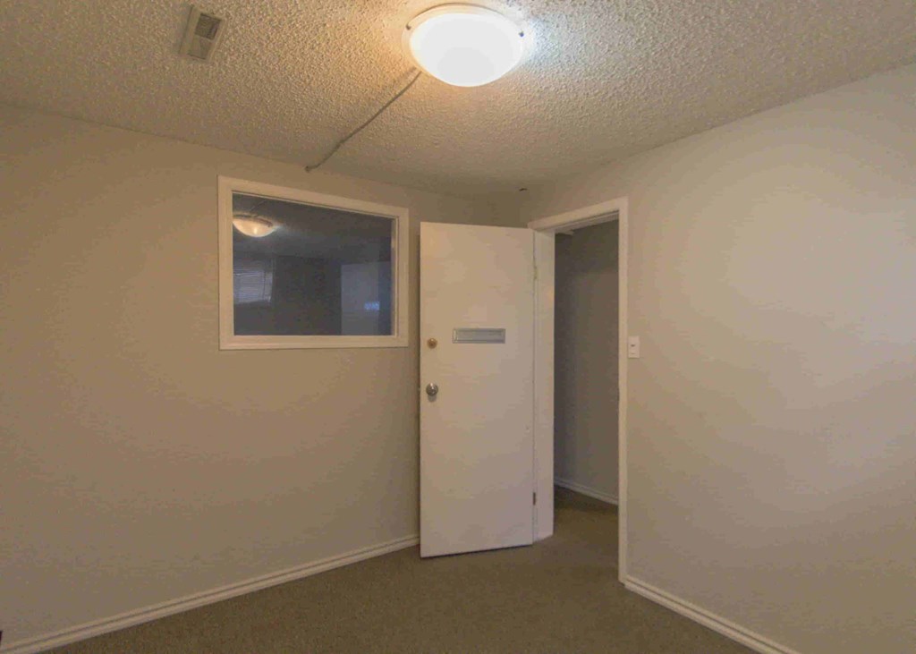 a room with a white door and a window and a door to a closet