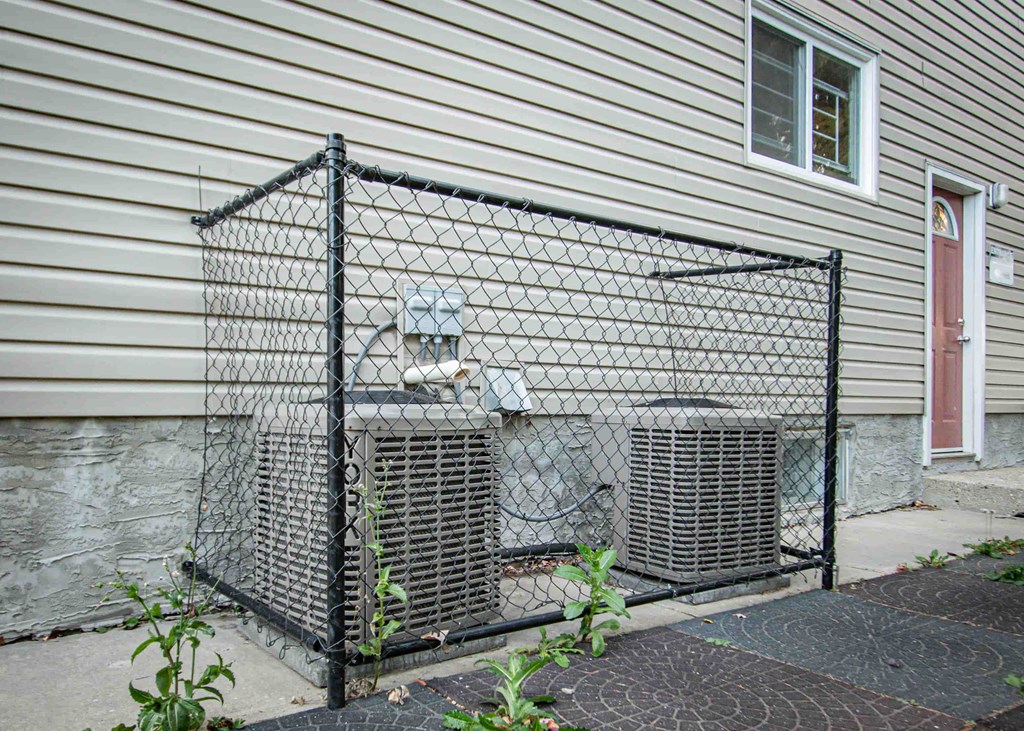 a house with a chain link fence and two air conditioning units