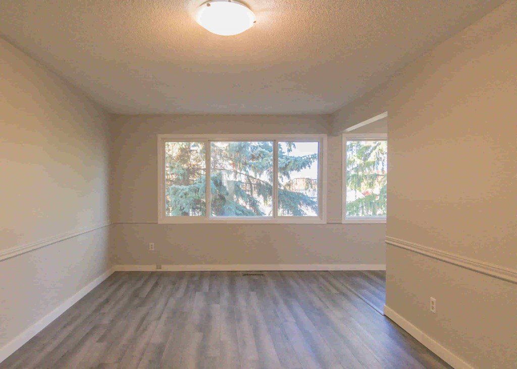 an empty living room with wood floors and a window
