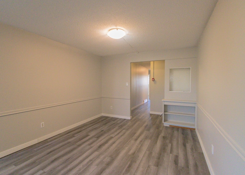 a living room with wood floors and a door to a hallway