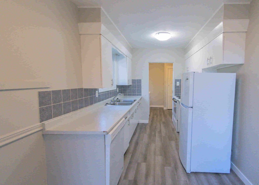 a kitchen with white cabinets and a white refrigerator