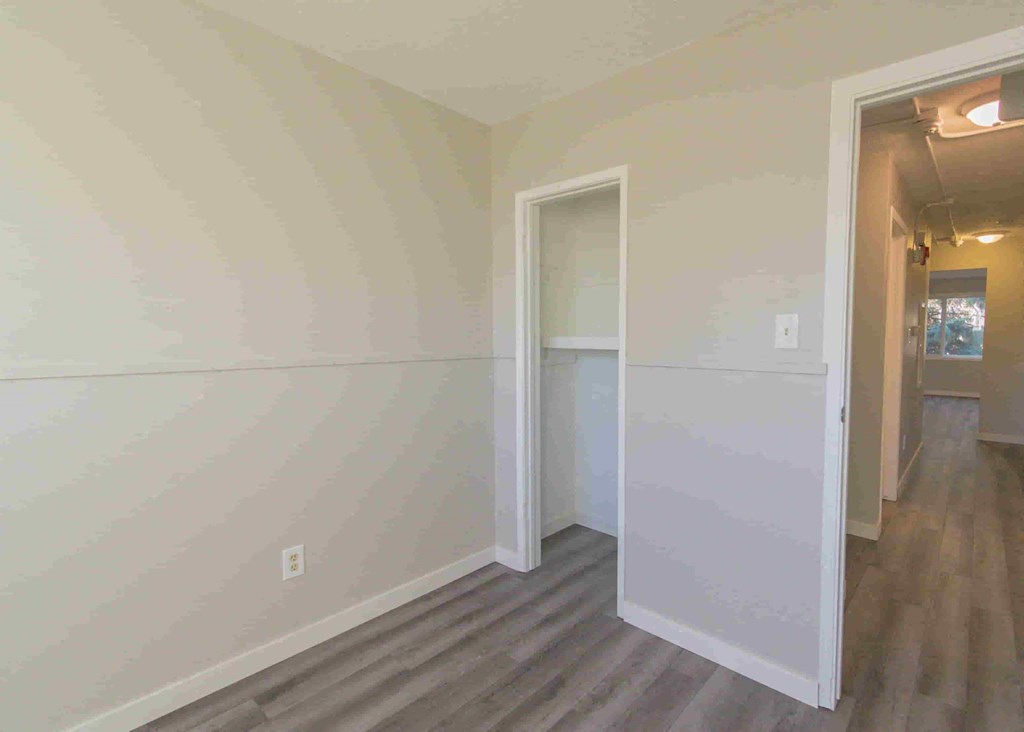 a bedroom with white walls and a door to a closet