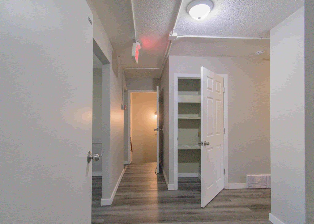 a hallway with a white door and a closet with a door open