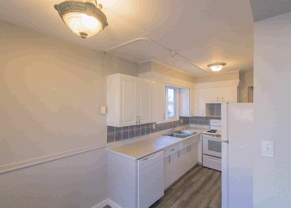 a kitchen with white cabinets and a sink and a refrigerator