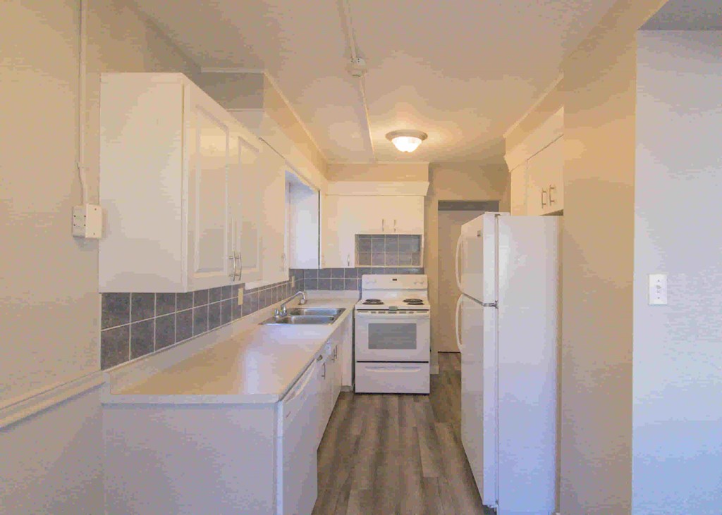 a kitchen with white cabinets and a sink and a refrigerator