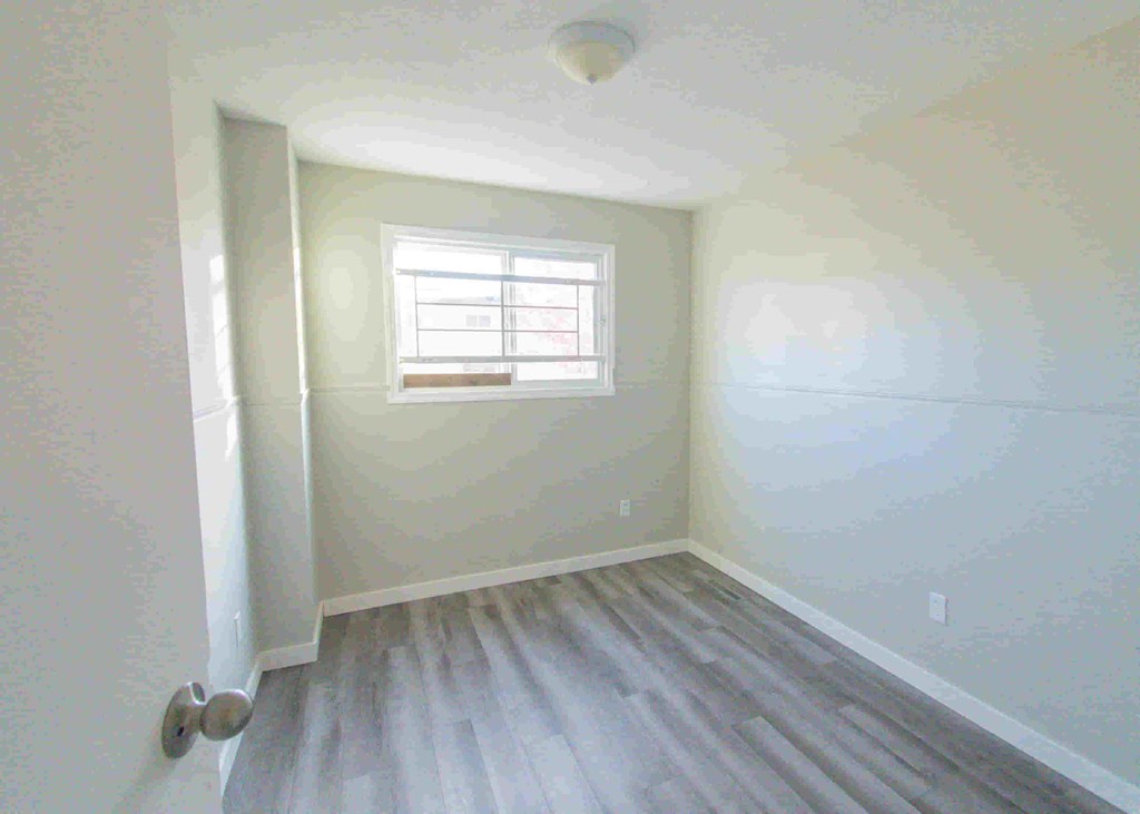 a room with white walls and a window and wooden floors