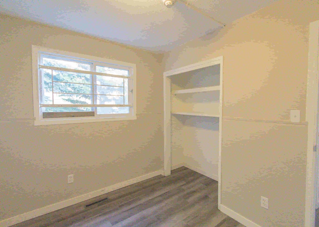 an empty room with a window and a book shelf
