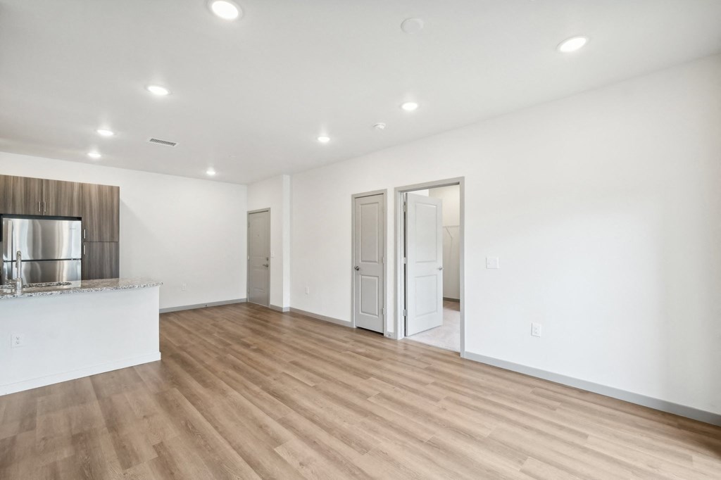 the living room and kitchen of a new home with white walls and wood flooring