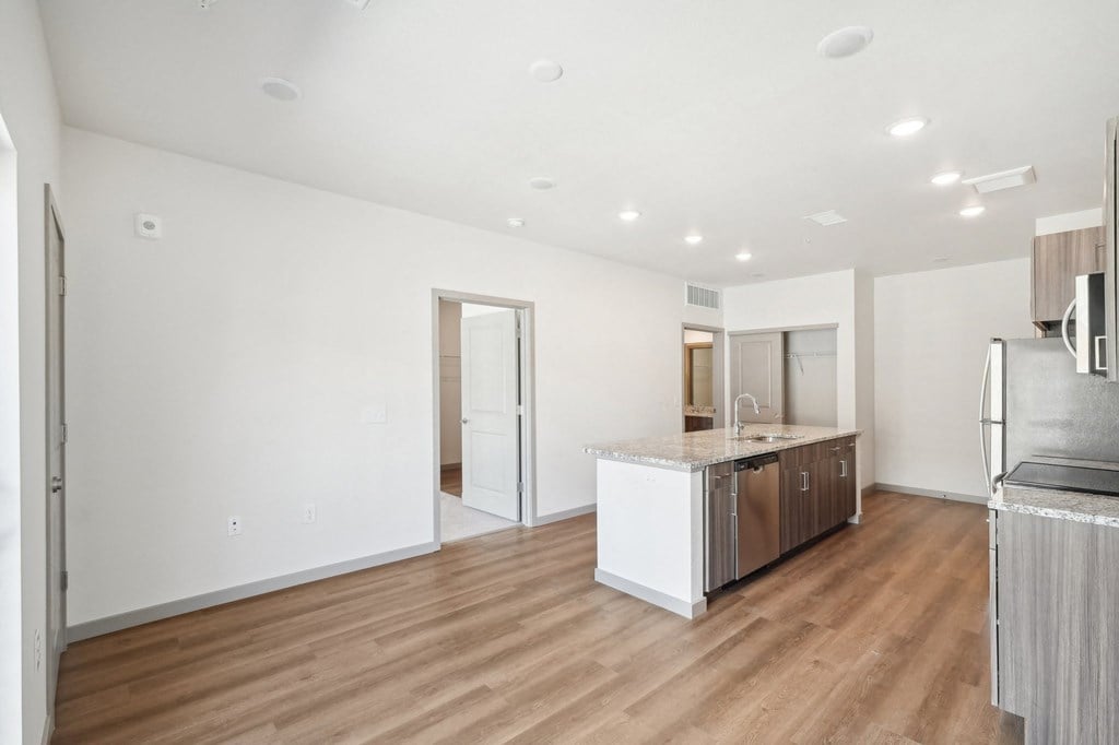 a living room with a kitchen and a refrigerator and a sink