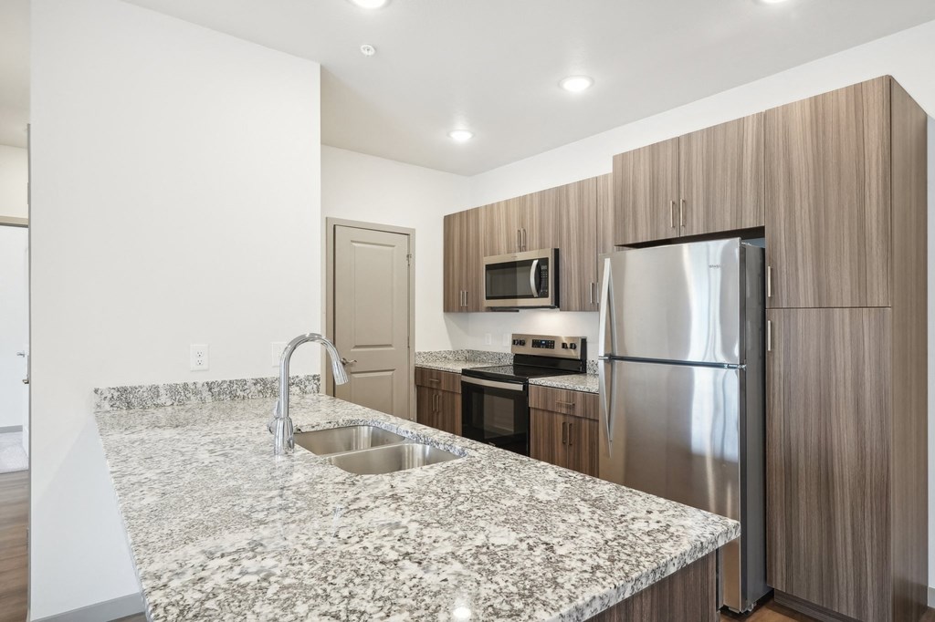 a kitchen with granite counter tops and a stainless steel refrigerator