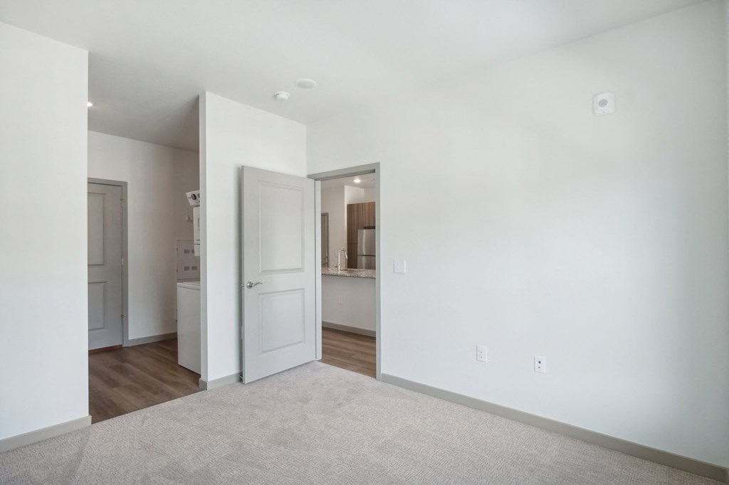 a living room with white walls and a door to a bathroom