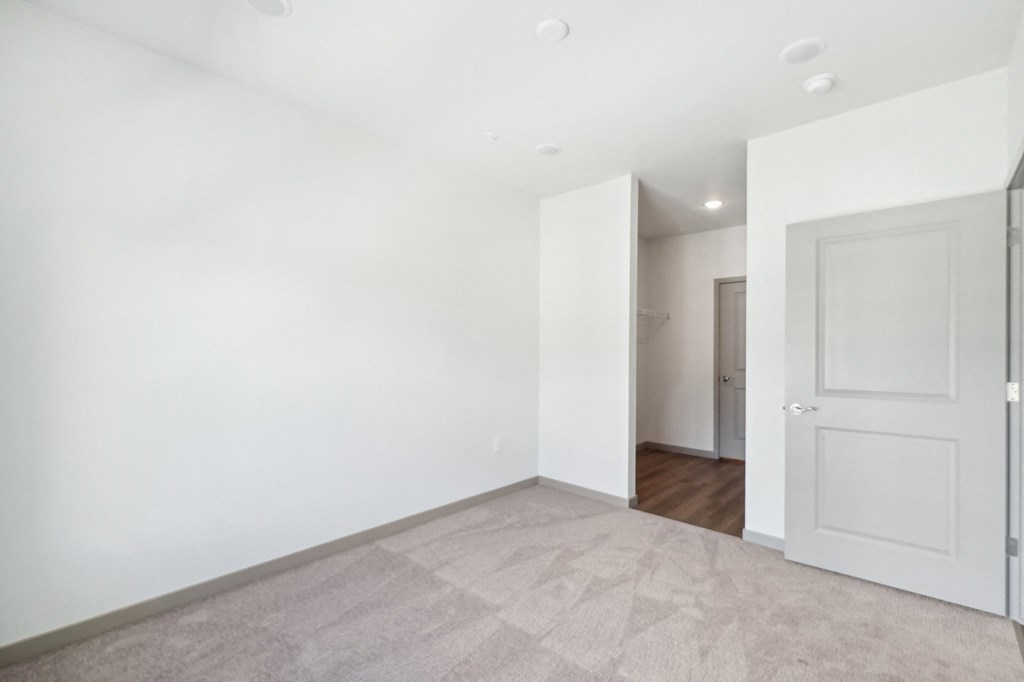 a living room with white walls and a door to a hallway