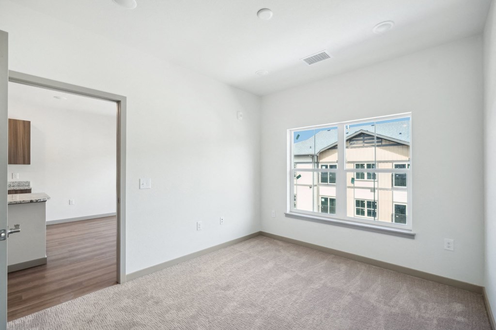 a living room with a large window and a door to a kitchen